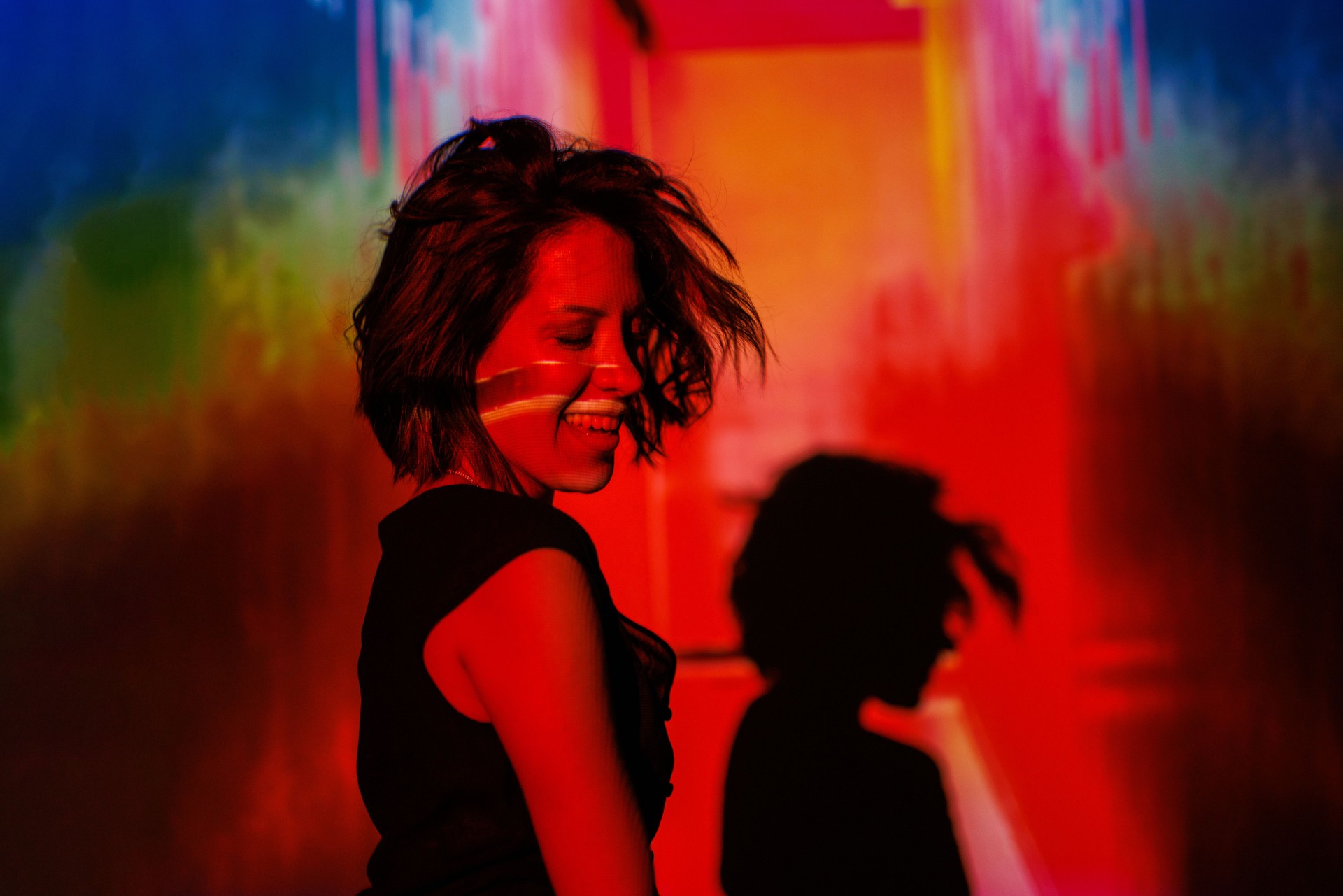Woman smiling in vibrant light with colorful patterns and creative shadow effects